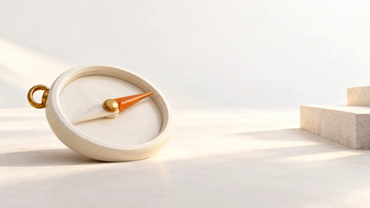 An unmarked ivory compass with an orange pointer facing a grounded stone step