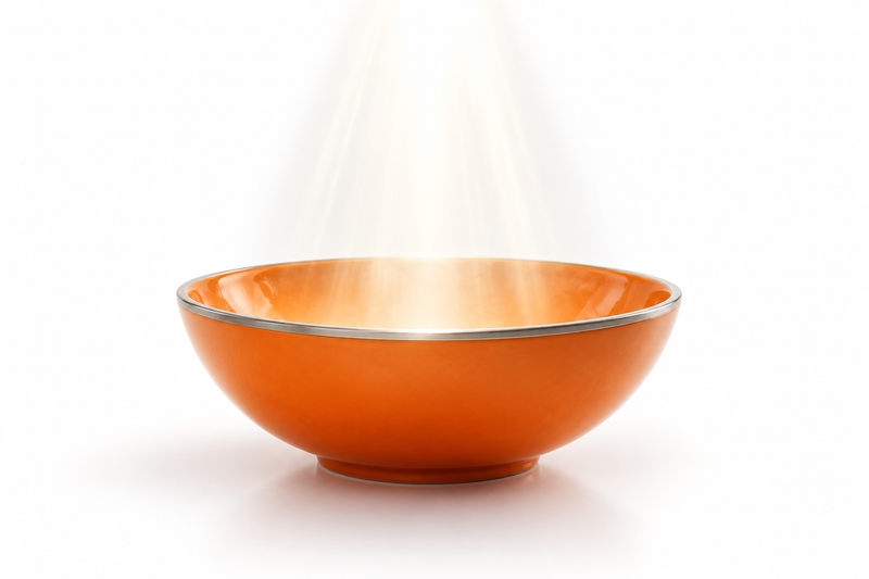 An orange ceramic vessel receiving white light against a clean white background, representing prayer and humble intention