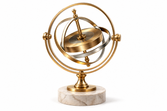 A polished brass gyroscope balanced on a pale stone base against a clean white background